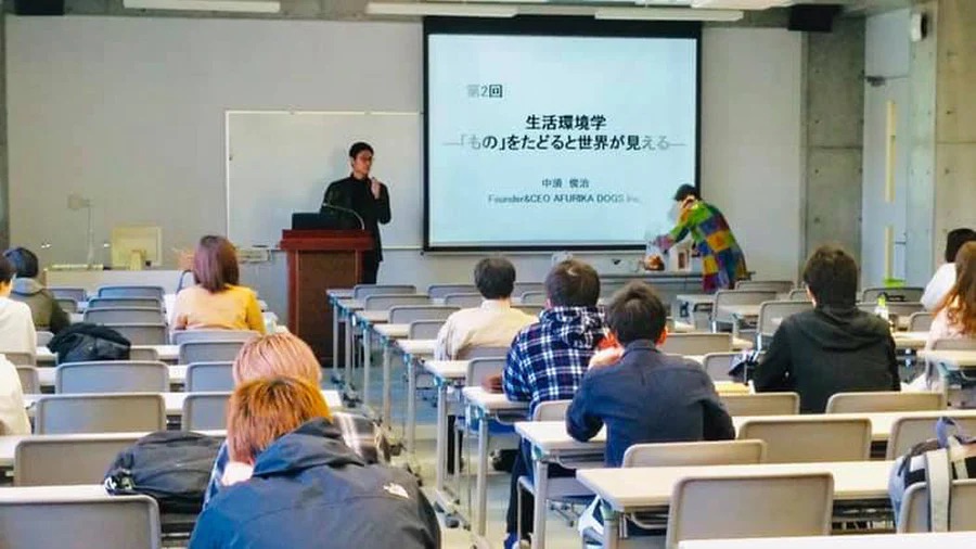SDGS・京都精華大学・特別講師 教壇で生活環境学のスライドを説明している